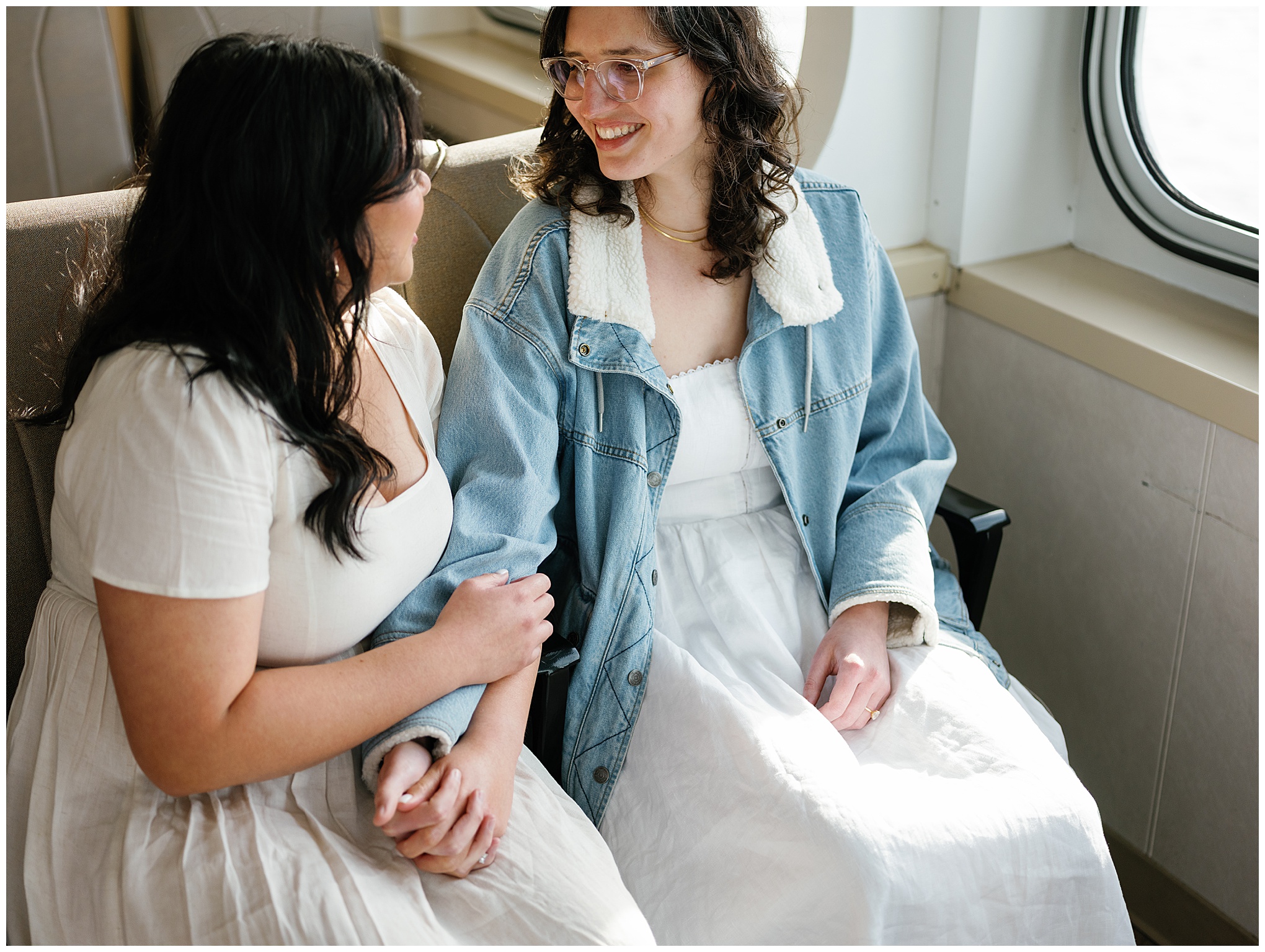 Carli and Erin sitting close and holding hands on the ferryboat.