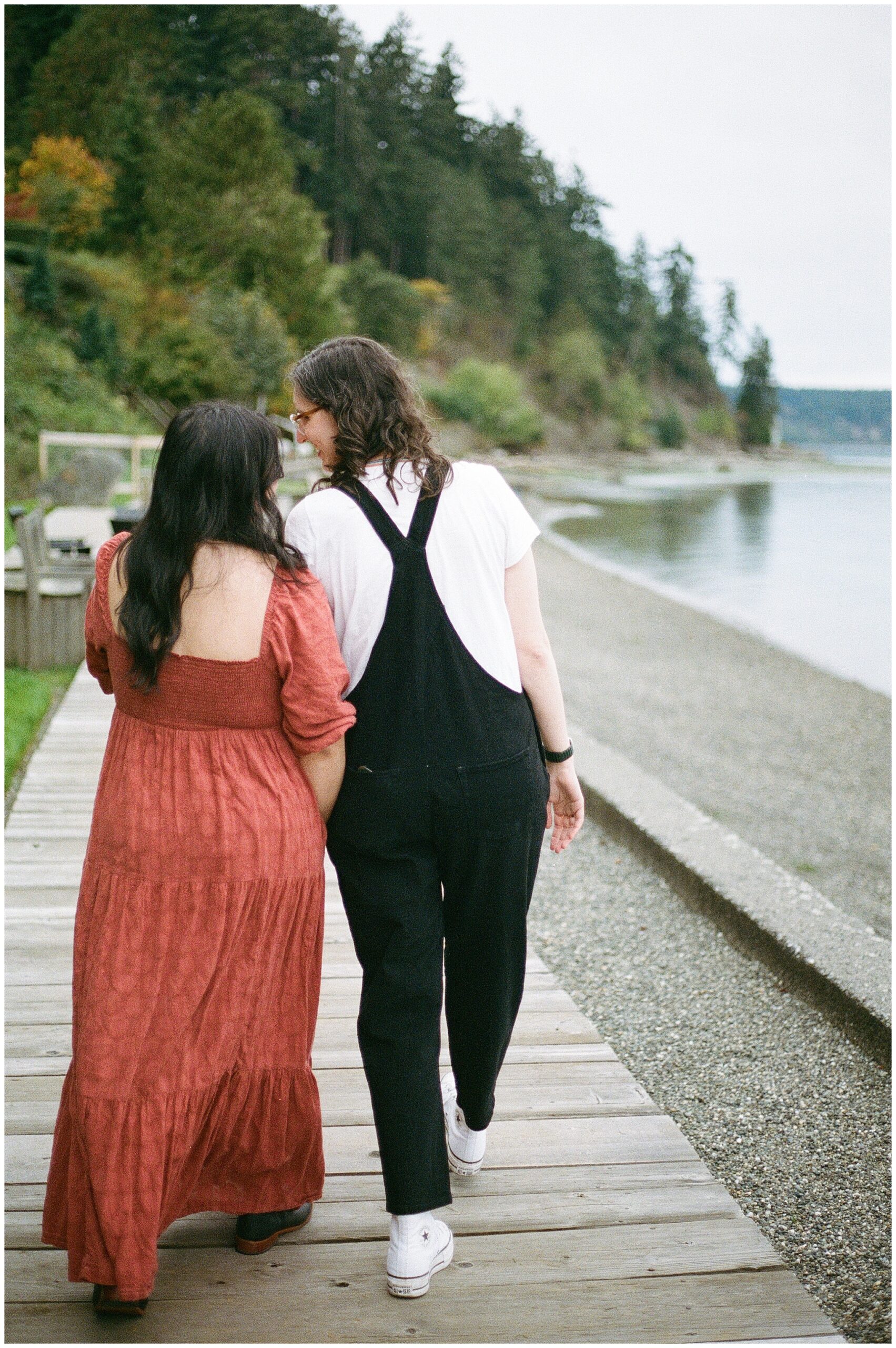 Carli and Erin walk along a wooden boardwalk by the beach.