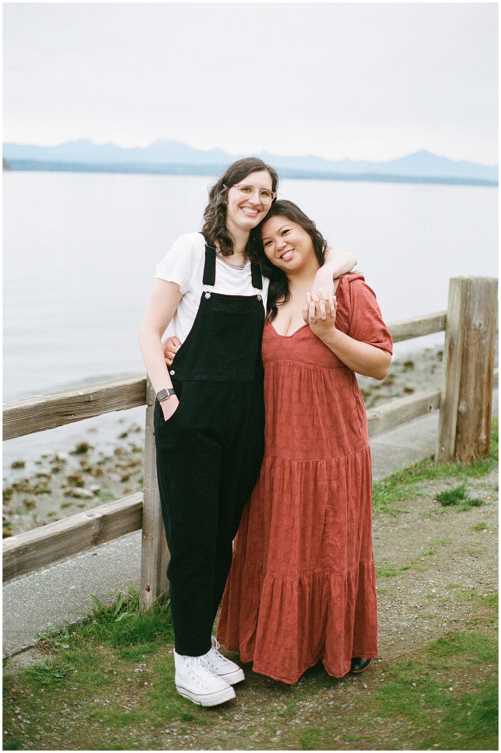 Couple standing together by the water with mountains in the background