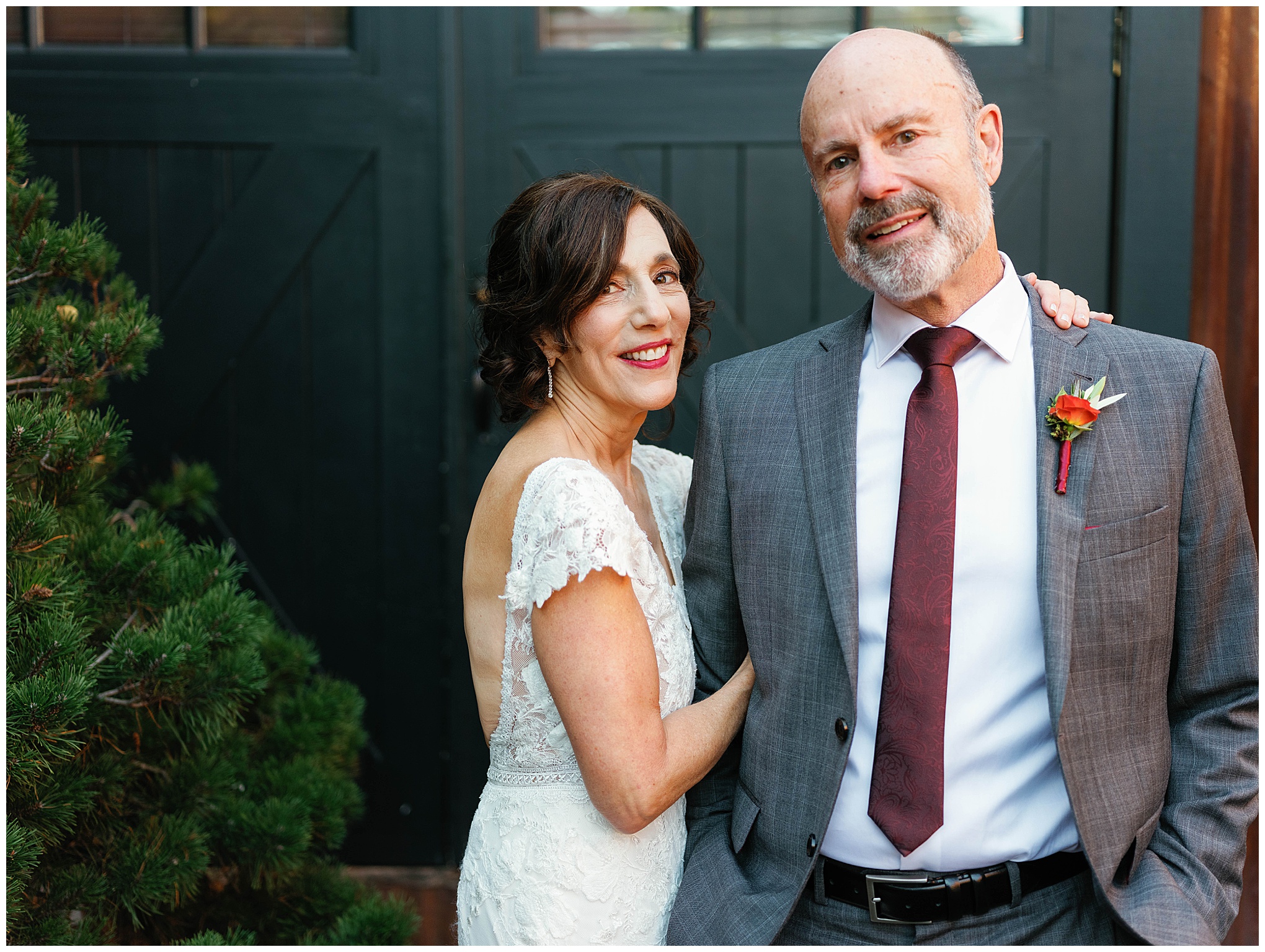 Bride standing beside groom, arm around his shoulder.