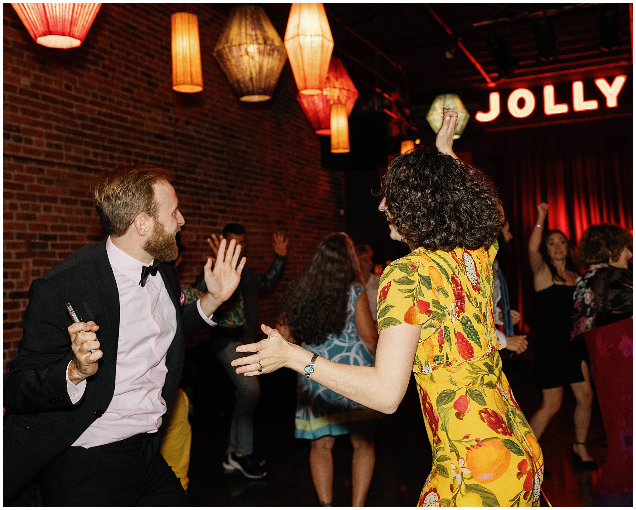 Wedding guests enjoying the dance floor under colorful lanterns.
