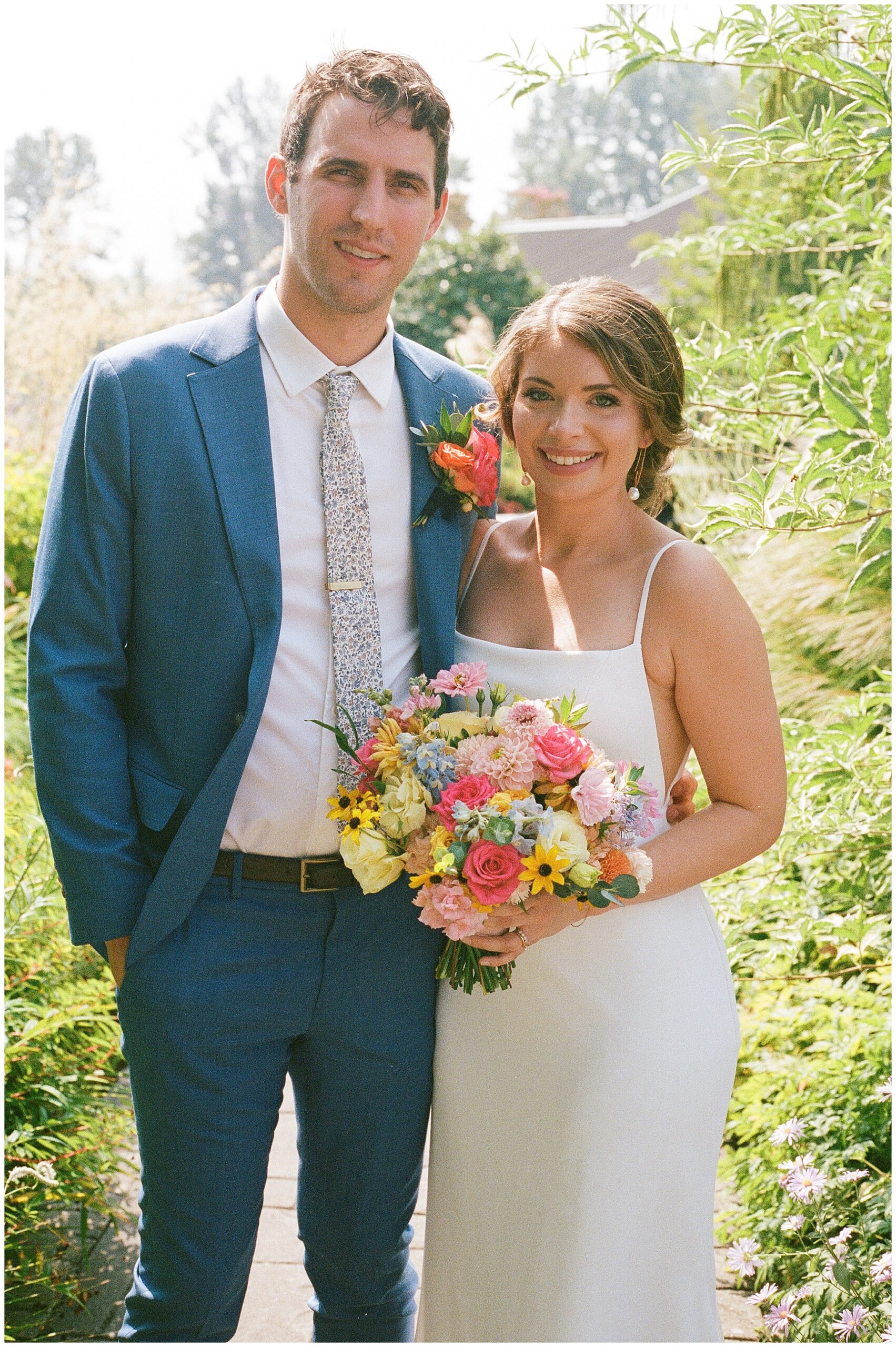 Close-up of the bride and groom with a colorful bouquet.