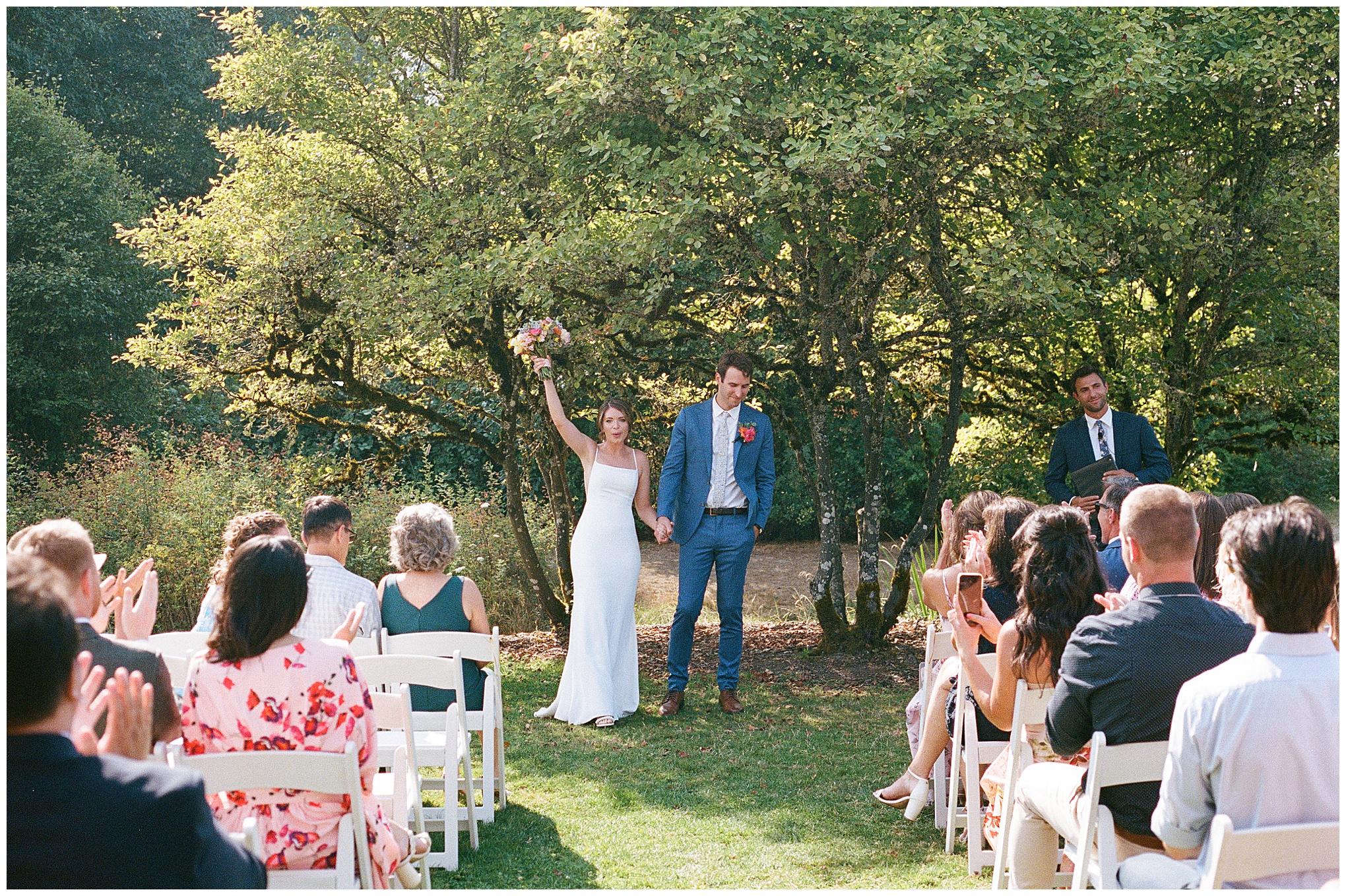 Grace and Chris celebrate their marriage, holding hands and raising a bouquet at the Center for Urban Horticulture