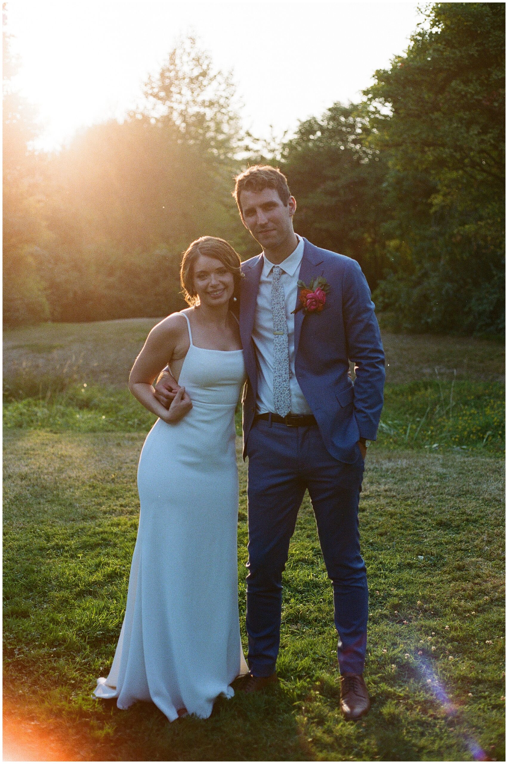 Grace and Chris pose together, smiling at the camera with the sun setting behind them at the Center for Urban Horticulture.