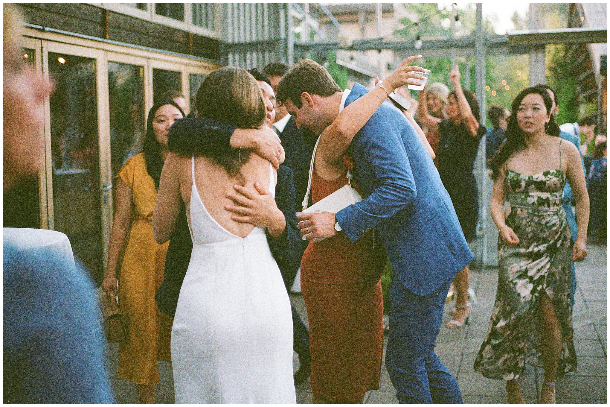 Grace and Chris hugging their friends during the wedding reception at the Center for Urban Horticulture.