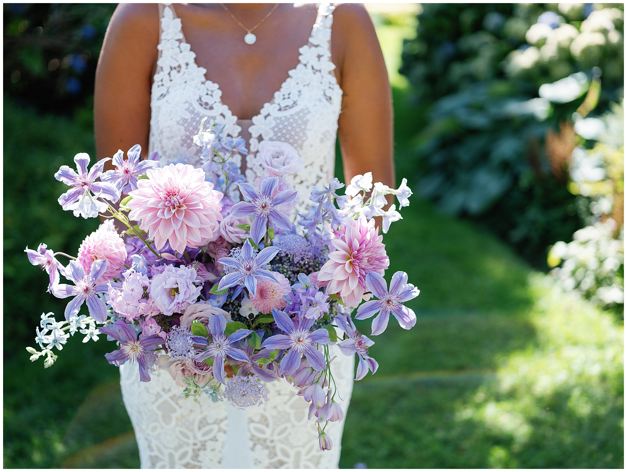 Close-up of bride's pastel bouquet featuring dahlias, roses, and delphiniums.