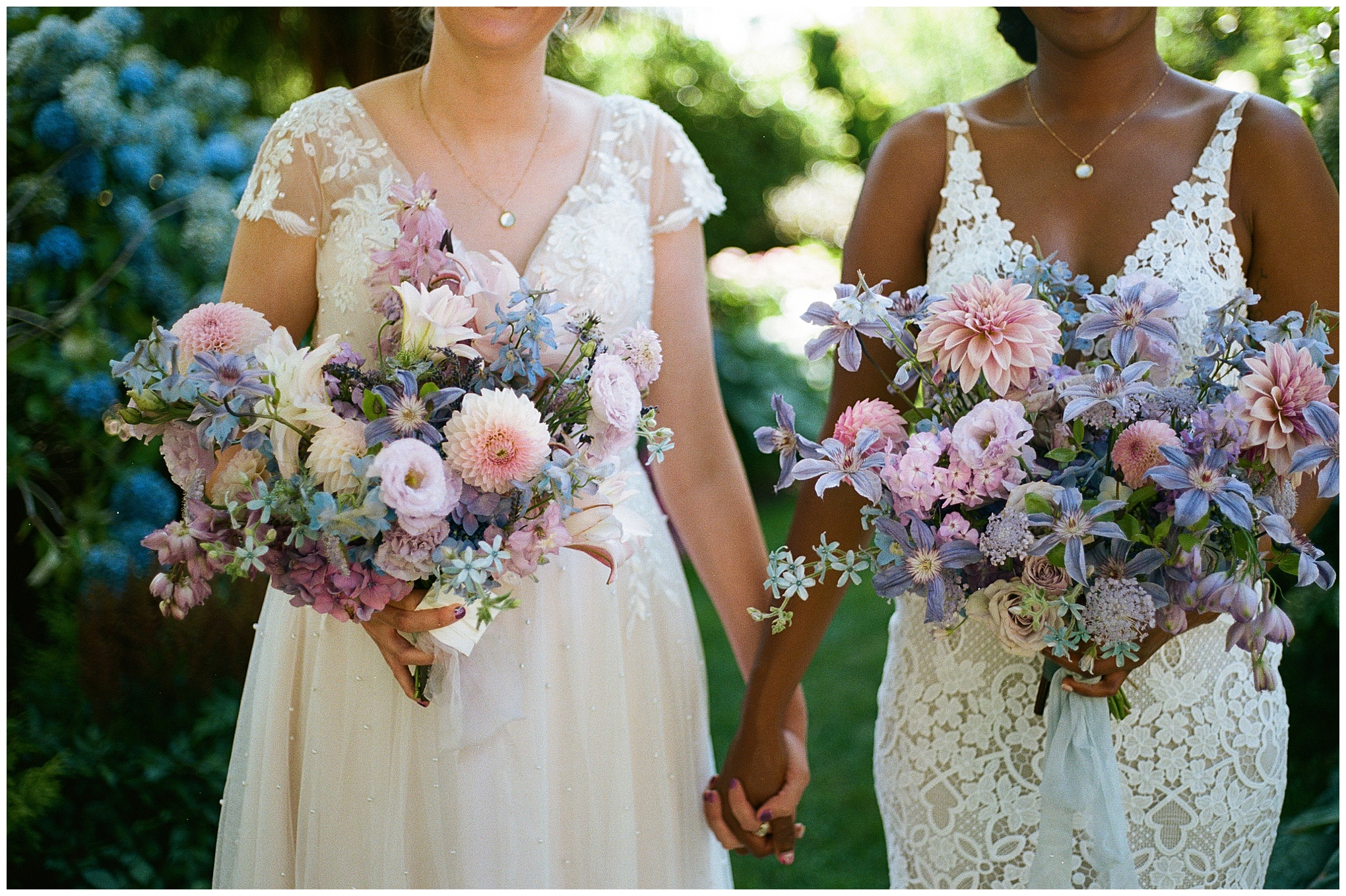 Close-up of the brides' hands holding vibrant bouquets of purple and pink flowers, showcasing delicate floral details.