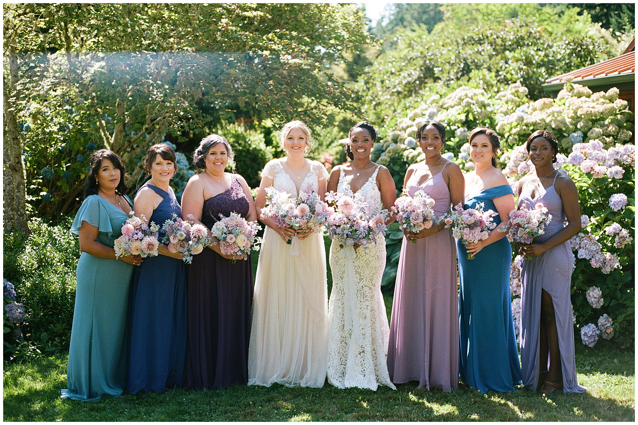 Brides and bridesmaids posing with pastel bouquets in the garden.