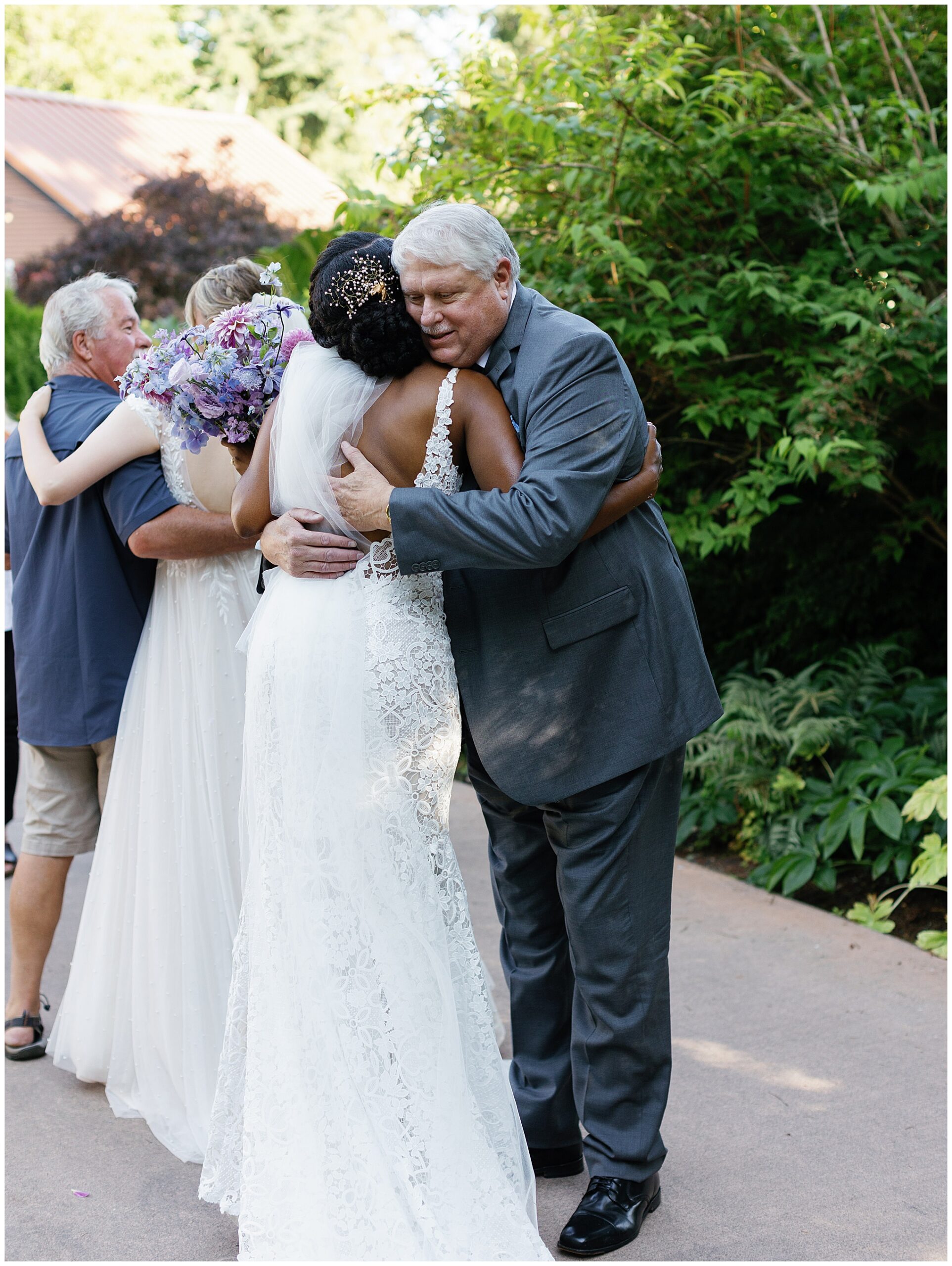 One of the brides hugging an elder male guest, both smiling warmly.