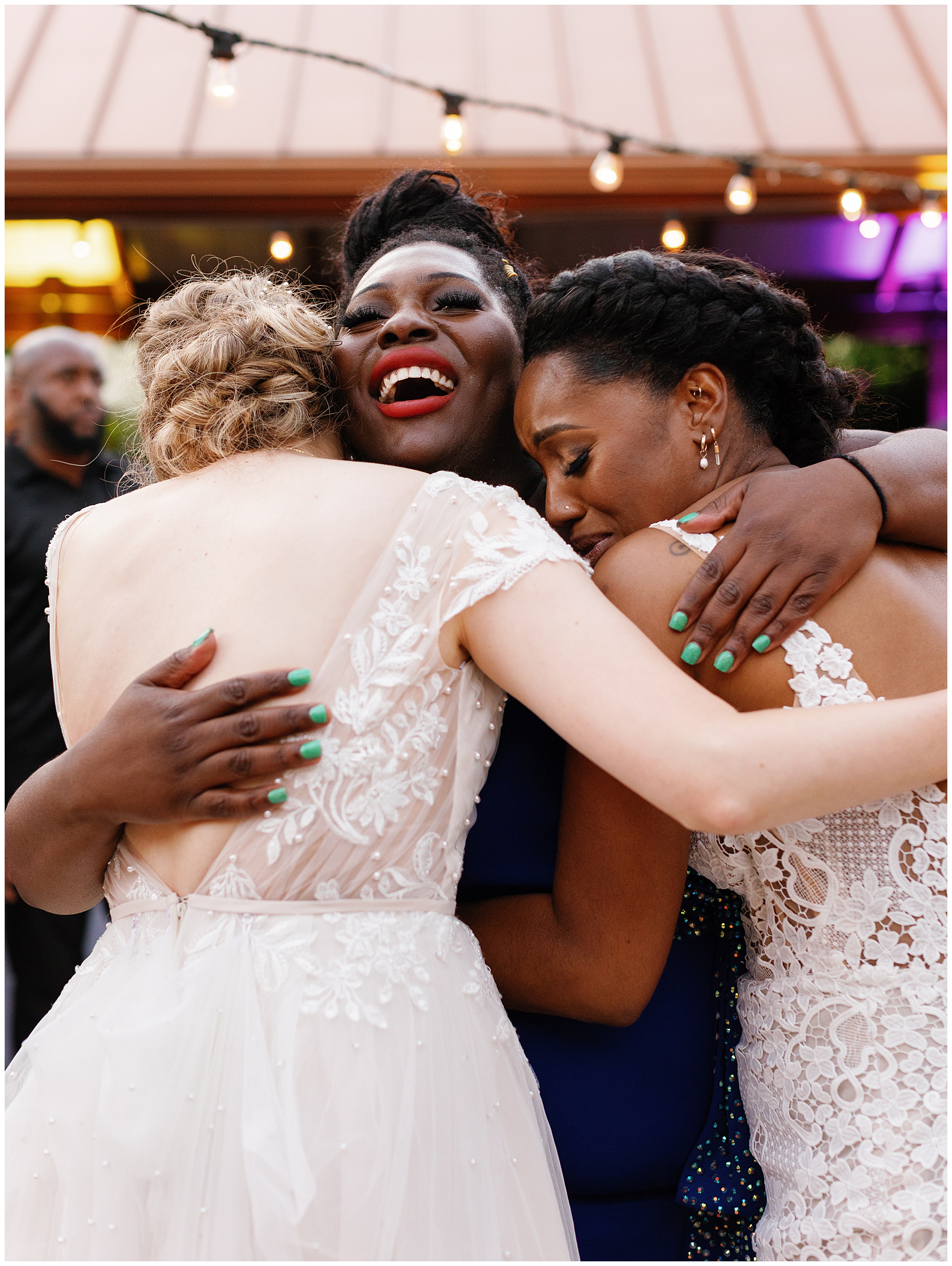 A joyful group hug between the couple and a friend, full of smiles and laughter.