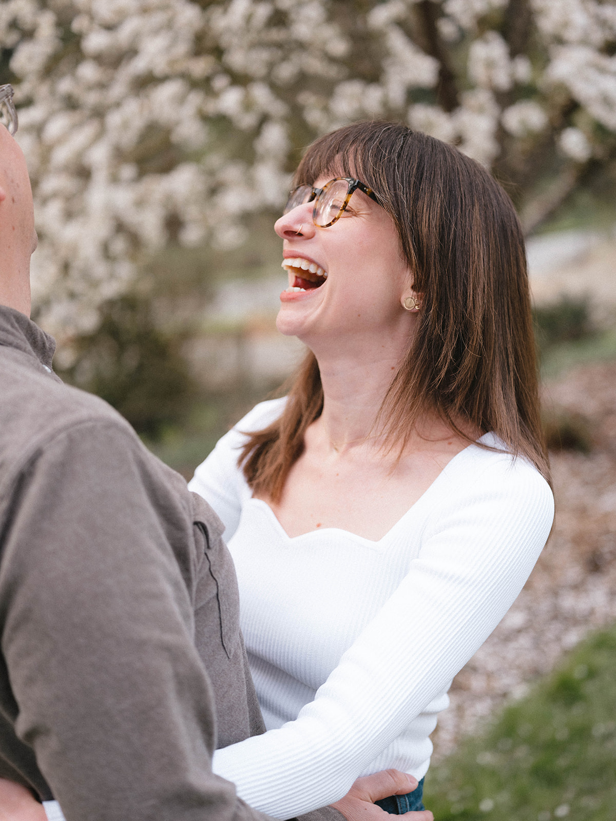 Charlotte laughing joyfully while looking at Grant, surrounded by blooming cherry blossoms.