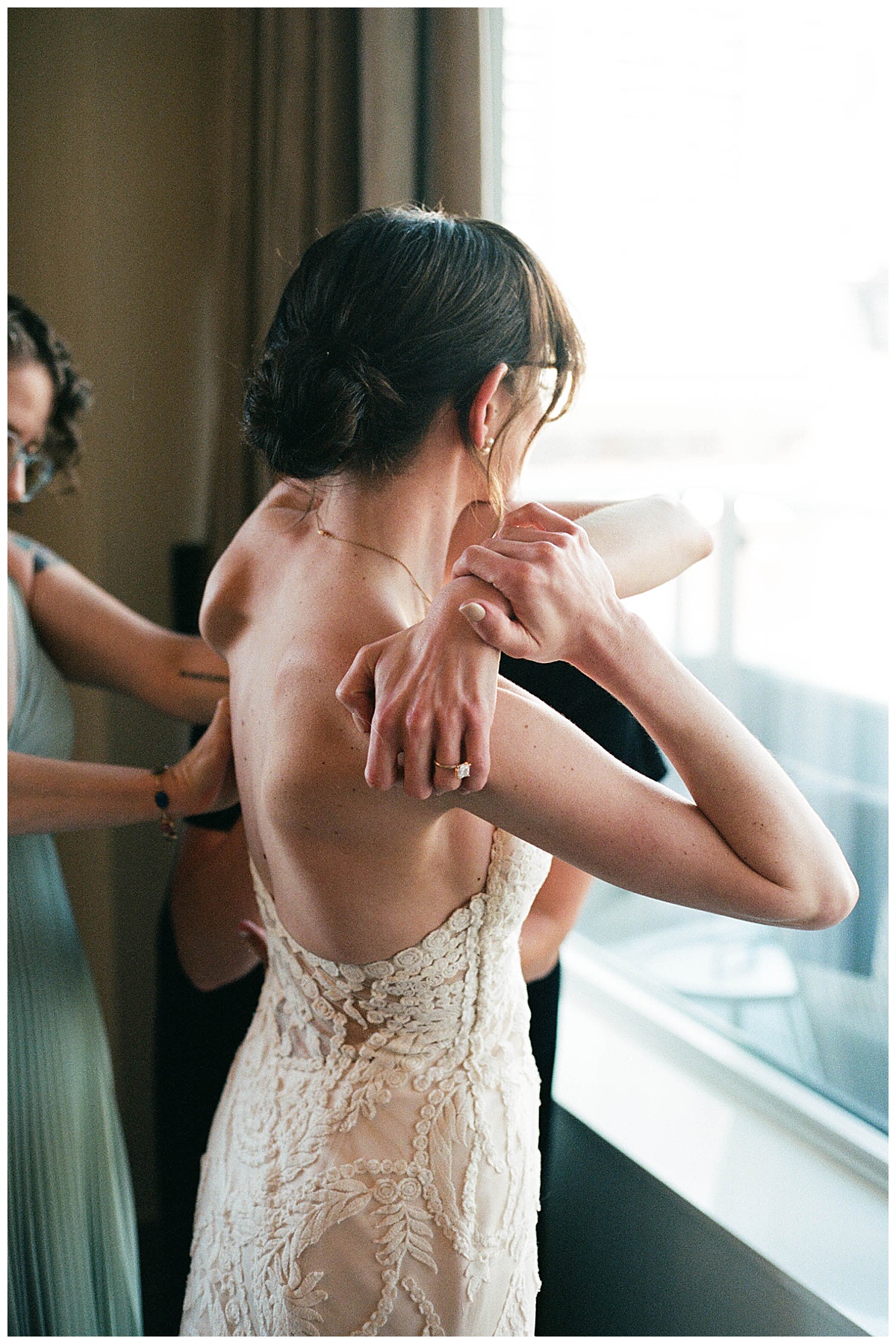 Charlotte getting ready, adjusting her gown as light filters through the window.