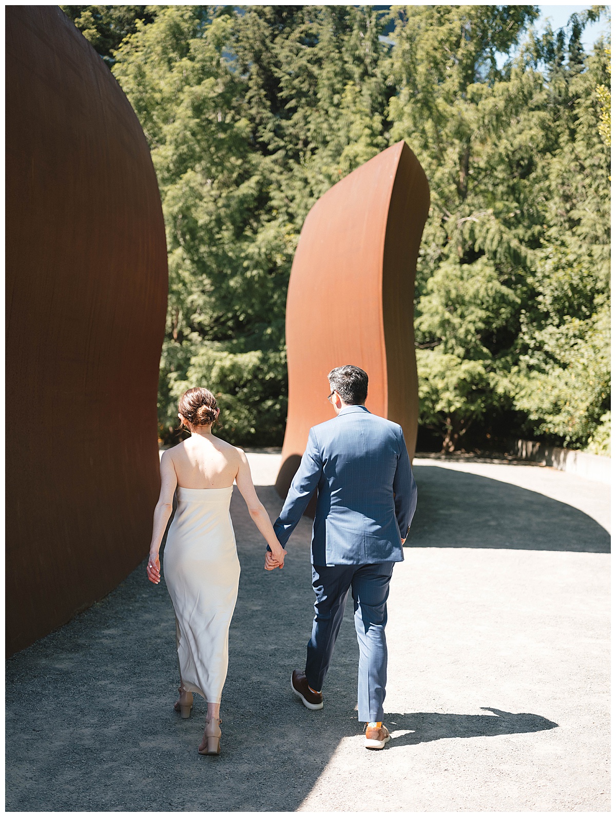 Bride and groom walk hand in hand through a modern sculptures at Olympic Sculpture garden.