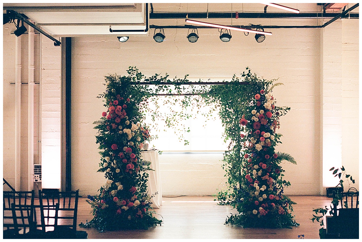 A floral arch adorned with colorful blooms and greenery for Charlotte and Grant's ceremony.