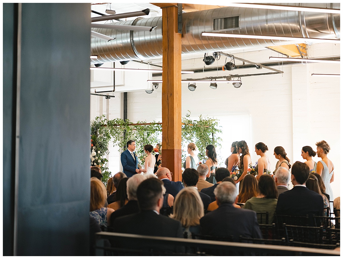 Wedding ceremony in progress, with the wedding party and guests looking on.