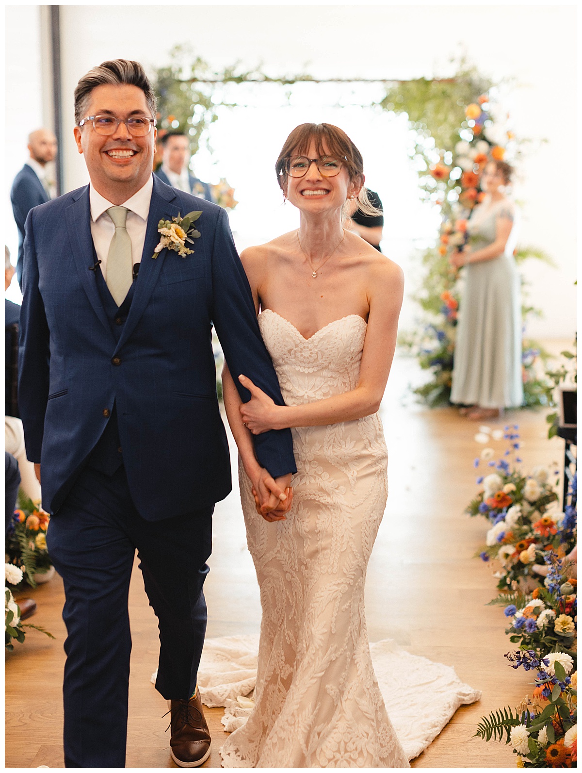 Bride and groom walking down the aisle after the ceremony, holding hands with wide smiles.