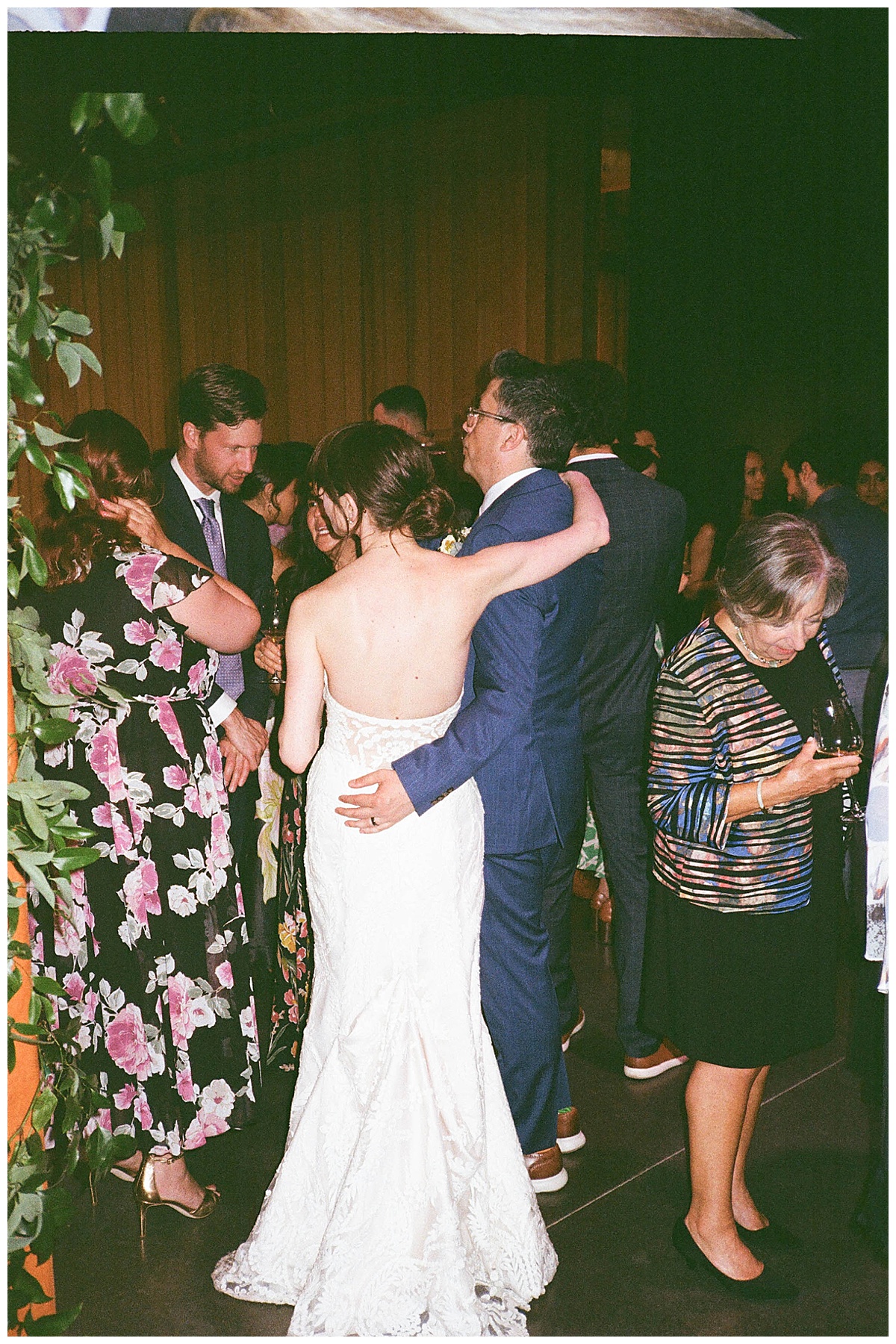 A newly married couple embraces while surrounded by friends and family, creating an intimate and celebratory moment.