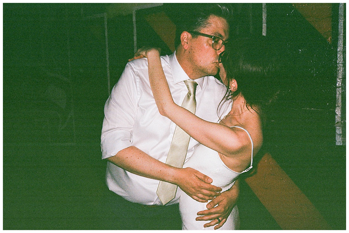 Groom leans in for a kiss as the couple shares an intimate moment in the evening light.