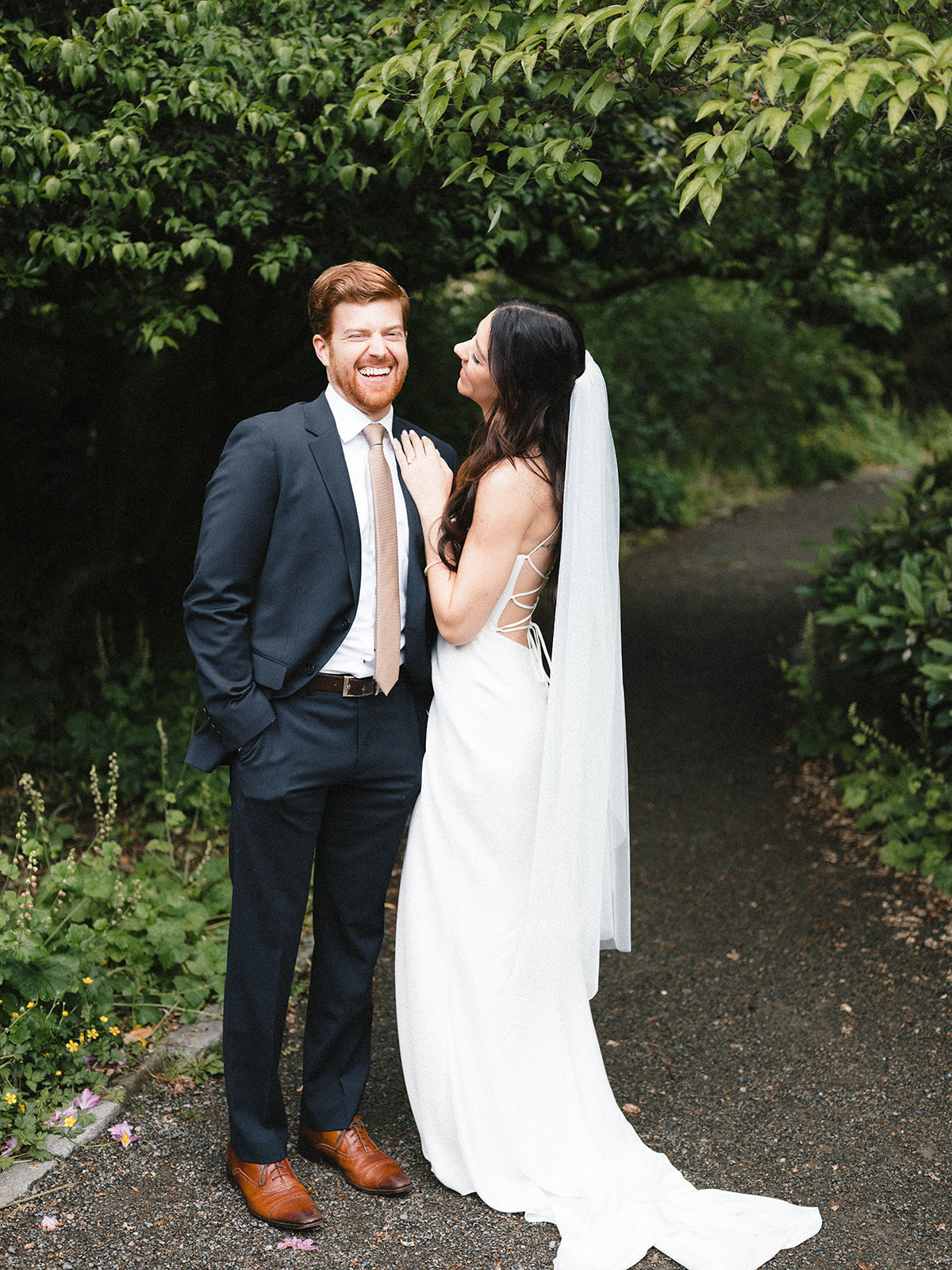 Bride and groom laughing together in a lush garden after their vow exchange, surrounded by greenery at Parsons Gardens.