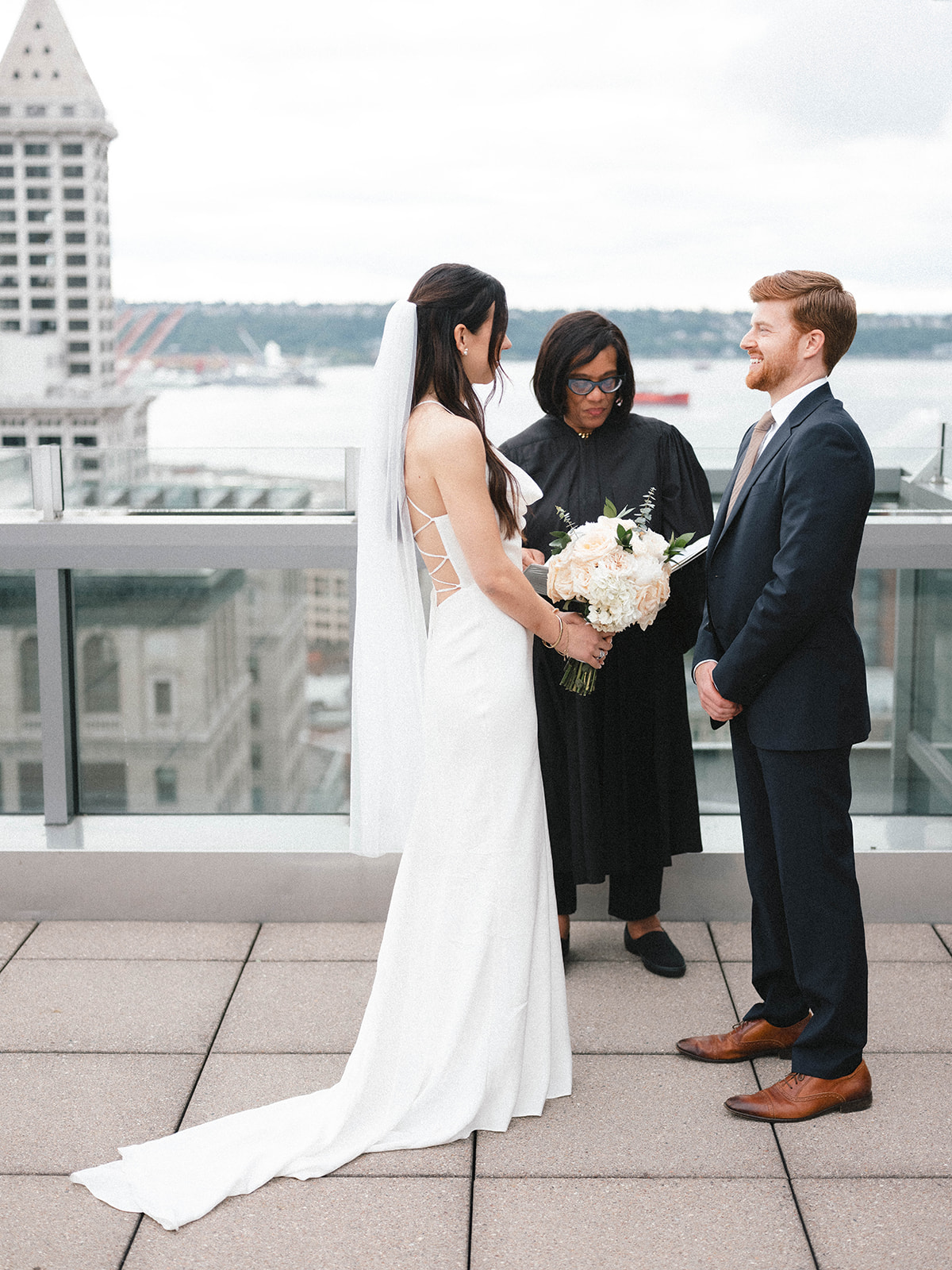 Beth and Robbie exchanging vows on a rooftop overlooking downtown Seattle with Judge Faye Chess officiating.