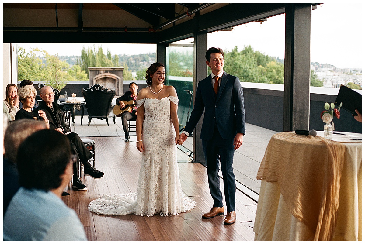 Newlyweds holding hands and smiling as they walk down the aisle after their wedding ceremony.