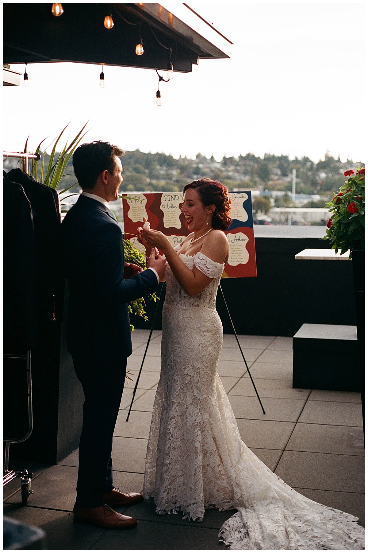 Bride and groom laughing and sharing a lighthearted moment on the rooftop during their wedding reception.