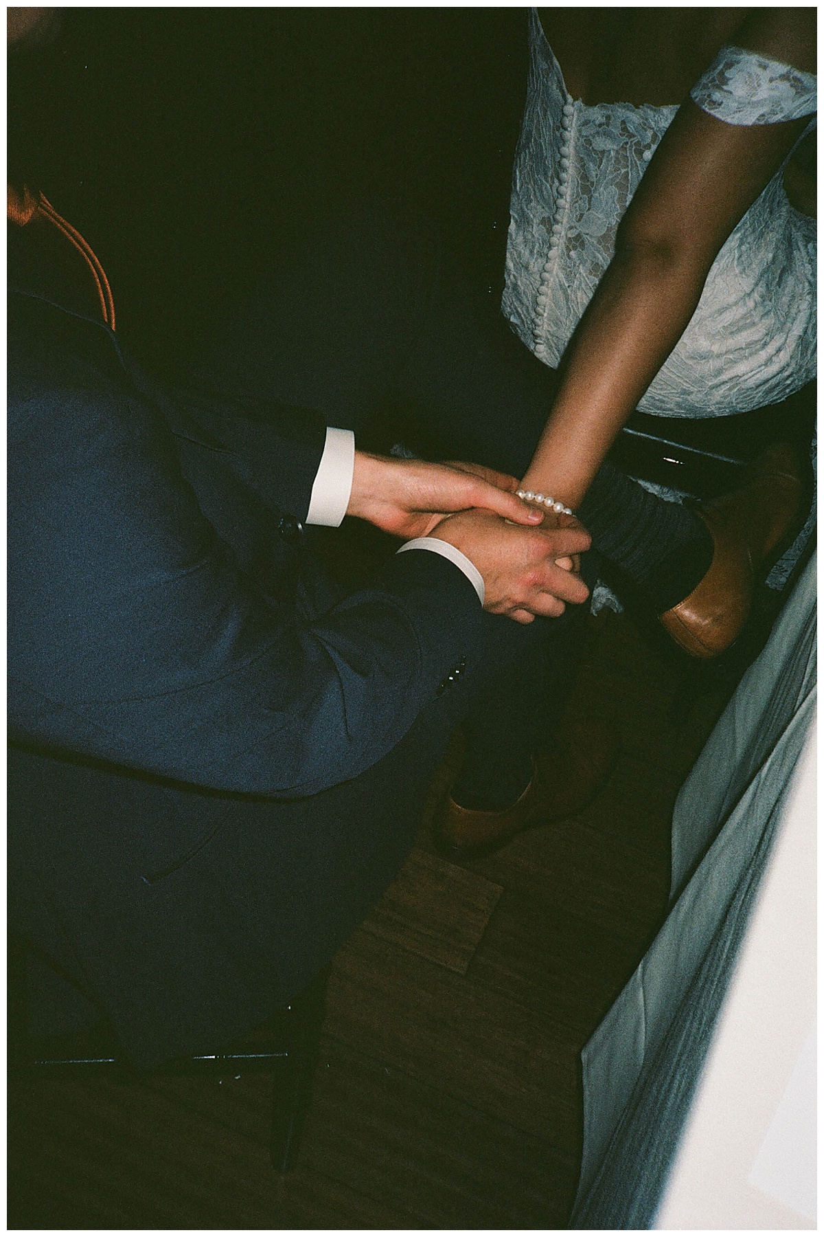 Intimate close-up of the bride and groom holding hands, showcasing their wedding rings and loving connection.